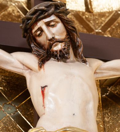 Zdjęcie nr 3: Wizerunek Chrystusa przybitego trzema gwoździami do krzyża łacińskiego.  Ciało wyprostowane, ręce rozciągnięte do boku, nogi delikatnie ugięte w kolanach, prawe powyżej lewego. Głowa opada na prawy bark. Jezus ma owalną twarz, usta i oczy zamknięte, nos prosty, brwi opadające w dół; okala ją dzieląca się w pukle broda oraz zwijające się w fale włosy opadające na plecy i barki. Na głowie korona cierniowa. Na prawym boku związane złote perizonium, którego końce opadają kaskadowo w dół, sięgając wysokości kolan. Z miejsc przebić gwoździami oraz z rany w boku sączy się krew. Krzyż gładki, na górnej belce titulus w formie zwoju z literami „IN/RI”. W tle trybowana złota blacha, na niej w dolnej części panorama Jerozolimy, w górnej kratownica z rozetkami na przecięciach. 
Polichromia w partiach ciała naturalistyczna, krzyż ciemnobrązowy. 

