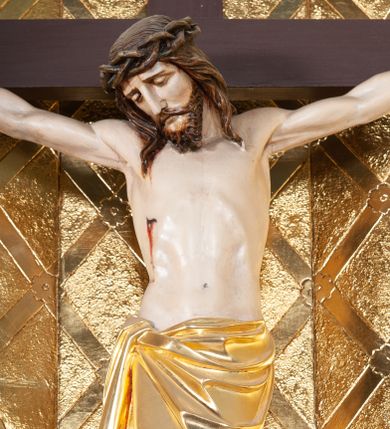 Zdjęcie nr 1: Wizerunek Chrystusa przybitego trzema gwoździami do krzyża łacińskiego.  Ciało wyprostowane, ręce rozciągnięte do boku, nogi delikatnie ugięte w kolanach, prawe powyżej lewego. Głowa opada na prawy bark. Jezus ma owalną twarz, usta i oczy zamknięte, nos prosty, brwi opadające w dół; okala ją dzieląca się w pukle broda oraz zwijające się w fale włosy opadające na plecy i barki. Na głowie korona cierniowa. Na prawym boku związane złote perizonium, którego końce opadają kaskadowo w dół, sięgając wysokości kolan. Z miejsc przebić gwoździami oraz z rany w boku sączy się krew. Krzyż gładki, na górnej belce titulus w formie zwoju z literami „IN/RI”. W tle trybowana złota blacha, na niej w dolnej części panorama Jerozolimy, w górnej kratownica z rozetkami na przecięciach. 
Polichromia w partiach ciała naturalistyczna, krzyż ciemnobrązowy. 
