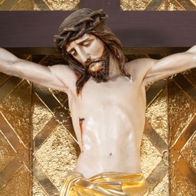 Zdjęcie nr 1: Wizerunek Chrystusa przybitego trzema gwoździami do krzyża łacińskiego.  Ciało wyprostowane, ręce rozciągnięte do boku, nogi delikatnie ugięte w kolanach, prawe powyżej lewego. Głowa opada na prawy bark. Jezus ma owalną twarz, usta i oczy zamknięte, nos prosty, brwi opadające w dół; okala ją dzieląca się w pukle broda oraz zwijające się w fale włosy opadające na plecy i barki. Na głowie korona cierniowa. Na prawym boku związane złote perizonium, którego końce opadają kaskadowo w dół, sięgając wysokości kolan. Z miejsc przebić gwoździami oraz z rany w boku sączy się krew. Krzyż gładki, na górnej belce titulus w formie zwoju z literami „IN/RI”. W tle trybowana złota blacha, na niej w dolnej części panorama Jerozolimy, w górnej kratownica z rozetkami na przecięciach. 
Polichromia w partiach ciała naturalistyczna, krzyż ciemnobrązowy. 

