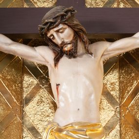 Zdjęcie nr 1: Wizerunek Chrystusa przybitego trzema gwoździami do krzyża łacińskiego.  Ciało wyprostowane, ręce rozciągnięte do boku, nogi delikatnie ugięte w kolanach, prawe powyżej lewego. Głowa opada na prawy bark. Jezus ma owalną twarz, usta i oczy zamknięte, nos prosty, brwi opadające w dół; okala ją dzieląca się w pukle broda oraz zwijające się w fale włosy opadające na plecy i barki. Na głowie korona cierniowa. Na prawym boku związane złote perizonium, którego końce opadają kaskadowo w dół, sięgając wysokości kolan. Z miejsc przebić gwoździami oraz z rany w boku sączy się krew. Krzyż gładki, na górnej belce titulus w formie zwoju z literami „IN/RI”. W tle trybowana złota blacha, na niej w dolnej części panorama Jerozolimy, w górnej kratownica z rozetkami na przecięciach. 
Polichromia w partiach ciała naturalistyczna, krzyż ciemnobrązowy. 

