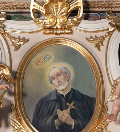 Zdjęcie nr 1: Obraz w kształcie stojącego owalu z przedstawieniem św. Andrzeja Boboli. Święty został ukazany w półpostaci, z rękami złożonymi na piersi, przytrzymując niewielki krucyfiks. Głowę ma przechyloną na prawo, wzrok skierowany do góry na objawiające się powyżej, otoczone glorią promienistą monogramy „IHS” i „MRA”. Bobola ma prostokątną twarz, uniesione brwi, wąski nos i nieznacznie rozchylone usta; twarz okala siwa broda, włosy krótkie. Jest ubrany w czarną sutannę i czarny, zarzucony na ramiona płaszcz z kołnierzem. Tło jest jednolite, szarozielone, jaśniejące wokół głowy świętego i wspomnianych monogramów. W dole przedstawienia inicjały artysty oraz data „J.P. 51 r.p.”. Obraz ujęto profilowaną, złoconą ramą.