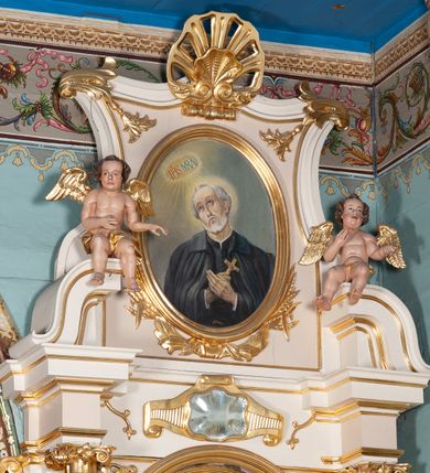 Zdjęcie nr 2: Obraz w kształcie stojącego owalu z przedstawieniem św. Andrzeja Boboli. Święty został ukazany w półpostaci, z rękami złożonymi na piersi, przytrzymując niewielki krucyfiks. Głowę ma przechyloną na prawo, wzrok skierowany do góry na objawiające się powyżej, otoczone glorią promienistą monogramy „IHS” i „MRA”. Bobola ma prostokątną twarz, uniesione brwi, wąski nos i nieznacznie rozchylone usta; twarz okala siwa broda, włosy krótkie. Jest ubrany w czarną sutannę i czarny, zarzucony na ramiona płaszcz z kołnierzem. Tło jest jednolite, szarozielone, jaśniejące wokół głowy świętego i wspomnianych monogramów. W dole przedstawienia inicjały artysty oraz data „J.P. 51 r.p.”. Obraz ujęto profilowaną, złoconą ramą.