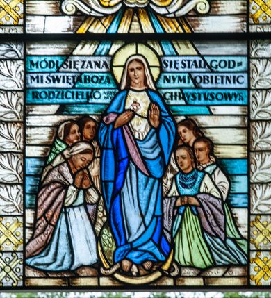 Zdjęcie nr 1: Witraż o wykroju prostokąta stojącego zakończonego łukiem odcinkowym nadwieszonym z przedstawieniem Serca Marii.  W centrum Maria stojąca na półksiężycu, depcząca węża. Lewą rękę wyciąga przed siebie, prawą zaś wskazuje na serce na piersi. Jest ubrana w białą tunikę i płaszcz w odcieniach błękitu. Wokół Marii klęczy sześć kobiet ubranych w stroje chłopskie, długie suknie, serdaki, korale, chusty na plecach i głowach. Scena otoczona bordiurą z dekoracją roślinną i geometryczną.Na wysokości głowy Marii inskrypcja: „MÓDL SIĘ ZA NA/MI ŚWIĘTA BOŻA / RODZICIELKO ABYŚMY / SIĘ STALI GOD/NYMI OBIETNIC / CHRYSTUSOWYCH”. Powyżej sceny kartusz wolutowy z literą „M” z krzyżem. Poniżej sceny kartusz z inskrypcją: „PRZECZYSTE / SERCE / MARII / BĄDŹ ZAWSZE / Z NAMI”. U dołu inskrypcja: „WITRAŻE / OFIAROWALI / PARAFIANIA / Z KRZĘCINA” . Poniżej „Witraże wykon(dalej niewidoczne) / S. G. ŻELEŃSKI / Projektował: / Wł(adysław). JASTRZĘBSKI” Witraż utrzymany w chłodnej kolorystyce, z przewagą szarości, niebieskiego i żółtego. 

