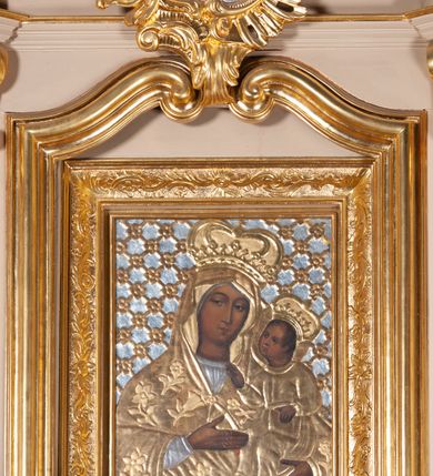 Zdjęcie nr 14: Ołtarz przyścienny, architektoniczny, na cokole, z bramkami. Nastawa jednoosiowa, jednokondygnacyjna ze zwieńczeniem. Mensa murowana, blat kamienny. Antepedium w kształcie leżącego prostokąta ujętego parami kolumn o gładkich trzonach i głowicach kompozytowych, podtrzymujących belkowanie z parami tryglifów. Belkowanie nad częścią środkową ucięte łukowato. W polu środkowym płaskorzeźbiona scena z przedstawieniem Świętej Rodziny. Postać św. Józefa półleżąca, zwrócona profilem w prawo, w stronę Matki Boskiej. Siedząca Maria skierowana w trzech czwartych w prawo, trzyma na kolanach poruszone Dzieciątko. Oś środkowa flankowana parą opilastrowanych filarów i kolumn o kapitelach kompozytowych, ustawionych przed licem ołtarza pod kątem. Podpory dźwigają pełne, wyłamane belkowanie oraz odpowiadający ich ułożeniu przerwany przyczółek. Zwieńczenie ujęte w spływy, zamknięte łukiem nadwieszonym. Cokoły kolumn dekorowane rocaille’em. W polu środkowym obraz we wnęce z przedstawieniem Matki Boskiej z Dzieciątkiem zasłaniany wizerunkiem św. Floriana w profilowanej ramie, w formie stojącego prostokąta zamkniętego dwoma, zwróconymi naprzeciwlegle stykającymi się spływami wolutowymi oraz rocaille’owym kartuszem z inskrypcją „POD TWOJĄ OBRONĘ”. Pierwsza kondygnacja ujęta uszakami utworzonymi z ornamentu rocaille’owego, ażurowej kratki regencyjnej i ornamentu roślinnego w formie kwiatów. Na bramkach ustawiono figury św. Wojciecha i św. Stanisława. Na przerwanym przyczółku spoczywa para adorujących aniołów. W zwieńczeniu profilowana rama powtarzająca jego formę z obrazem św. Antoniego Padewskiego zamknięta rocaille’em. Całość ujęta w spływy z ornamentu roślinnego. Struktura polichromowana na kremowo ze złoconą i srebrzoną ornamentyką oraz detalami architektonicznymi.