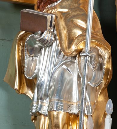 Zdjęcie nr 3: Ołtarz przyścienny, architektoniczny, na cokole, z bramkami. Nastawa jednoosiowa, jednokondygnacyjna ze zwieńczeniem. Mensa murowana, blat kamienny. Antepedium w kształcie leżącego prostokąta ujętego parami kolumn o gładkich trzonach i głowicach kompozytowych, podtrzymujących belkowanie z parami tryglifów. Belkowanie nad częścią środkową ucięte łukowato. W polu środkowym płaskorzeźbiona scena z przedstawieniem Świętej Rodziny. Postać św. Józefa półleżąca, zwrócona profilem w prawo, w stronę Matki Boskiej. Siedząca Maria skierowana w trzech czwartych w prawo, trzyma na kolanach poruszone Dzieciątko. Oś środkowa flankowana parą opilastrowanych filarów i kolumn o kapitelach kompozytowych, ustawionych przed licem ołtarza pod kątem. Podpory dźwigają pełne, wyłamane belkowanie oraz odpowiadający ich ułożeniu przerwany przyczółek. Zwieńczenie ujęte w spływy, zamknięte łukiem nadwieszonym. Cokoły kolumn dekorowane rocaille’em. W polu środkowym obraz we wnęce z przedstawieniem Matki Boskiej z Dzieciątkiem zasłaniany wizerunkiem św. Floriana w profilowanej ramie, w formie stojącego prostokąta zamkniętego dwoma, zwróconymi naprzeciwlegle stykającymi się spływami wolutowymi oraz rocaille’owym kartuszem z inskrypcją „POD TWOJĄ OBRONĘ”. Pierwsza kondygnacja ujęta uszakami utworzonymi z ornamentu rocaille’owego, ażurowej kratki regencyjnej i ornamentu roślinnego w formie kwiatów. Na bramkach ustawiono figury św. Wojciecha i św. Stanisława. Na przerwanym przyczółku spoczywa para adorujących aniołów. W zwieńczeniu profilowana rama powtarzająca jego formę z obrazem św. Antoniego Padewskiego zamknięta rocaille’em. Całość ujęta w spływy z ornamentu roślinnego. Struktura polichromowana na kremowo ze złoconą i srebrzoną ornamentyką oraz detalami architektonicznymi.