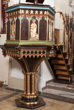 Zdjęcie nr 1: Ambona wolnostojąca, dostępna schodkami od strony prezbiterium, z pulpitem do czytania. Kosz sześcioboczny ustawiony na postumencie o przekroju wieloliścia utworzonym z wiązki kolumienek o złoconych bazach i trzonach zdobionych rytym ornamentem roślinnym, osadzonym na niskim, sześciobocznym cokole. U podstawy kosza ostrołukowy fryz arkadkowy. Ścianki kosza podzielone na trzy części dekoracją pseudomaswerkową w formie arkadek. W środkowej arkadce każdego z pól płaskorzeźbione, polichromowane i złocone przedstawienie ewangelistów:  św. Jana, św. Mateusza, św. Marka i św. Łukasza. Powyżej fryz ze stylizowanych lilii heraldycznych. Schody jednobiegowe, z balustradą utworzoną z rzędu wąskich kolumienek, ustawionych na niskich cokołach i bazach, o złoconych trzonach i półkolistych kapitelach. Każdy z ewangelistów ukazany całopostaciowo, frontalnie, z księgą w lewej ręce i piórem w prawej. U stóp ewangelistów przedstawiono odpowiadające im atrybuty: św. Marka – lew, św. Jana – orzeł, św. Mateusza – człowiek, św. Łukasza - wół. Ewangeliści, oprócz św. Jana mają rysy twarzy dojrzałych mężczyzn, z brodami, św. Jan bez brody z długimi i jasnymi włosami, opadającymi na plecy. Ubrani są w długie złocone suknie i złocone płaszcze. Struktura malowana na ciemny brąz, płyciny na kolor niebieski, zielony i czerwony, partie ornamentu złocone. 