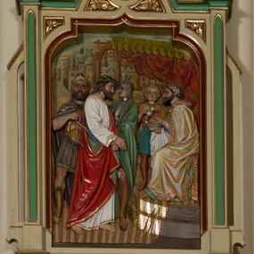 Zdjęcie nr 1: Czternaście płaskorzeźbionych, polichromowanych stacji drogi krzyżowej ukazanych na tle malowanego pejzażu. Przedstawienia ujęte w neogotyckie, architektoniczne ramy zamknięte wimpergą z żabkami, zwieńczoną  kwiatonem z krzyżem, pośrodku wimpergi czterolistna płycina z numerem stacji. Wnęka na płaskorzeźbę zamknięta łukiem dwuramiennym. Partia cokołowa ujęta od dołu podwieszeniem z rozetką. Polichromia ram w odcieniu kremowym, zielonym i ciemnoczerwonym z pozłacanym detalem. Sceny wielofigurowe z Chrystusem w centrum. Chrystus na większości przedstawień jest ubrany w długą, białą tunikę z pozłacaną lamówką i czerwony płaszcz z błękitną podszewką. Twarz owalna okolona ciemnymi włosami i ciemnym zarostem. W tle pejzaż z elementami architektury. Na stacji pierwszej, w prawym dolnym rogu napis „Ferd(inand) Stuflesser / Bildabauer / S(ank)t Ulrich Gröden Tirol / 1903”.