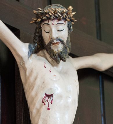 Zdjęcie nr 1: Pełnoplastyczna, polichromowana figura Chrystusa przybita do krzyża trzema gwoździami. Sylwetka zmarłego Chrystusa smukła, wychudła o naturalnej karnacji z lekko zaznaczoną muskulaturą i układem kostnym klatki piersiowej. Ramiona uniesione wysoko tworzą łuk, dłonie z wyprostowanymi palcami wskazującym i środkowym, nogi ugięte w kolanach. Głowa lekko pochylona, zwrócona w prawą stronę. Twarz podłużna, oczy zamknięte, nos długi, broda krótka rozdzielona na końcu w dwa pukle. Głowę okalają długie, kręcone włosy opadające na ramiona. Perizonium krótkie, ciasto oplatające biodra, spięte na lewym boku. Z boku, dłoni, stóp i spod korony cierniowej spływają strużki krwi. Polichromia ciała naturalistyczna. Krzyż gładki, prosty, pomalowany na ciemnobrązowy kolor. Nad głową barokowy titulus w formie kartusza z owalną płyciną w polu z napisem „INRI”, dekorowany ornamentem małżowinowo-chrząstkowym. Polichromia w odsłoniętych partiach ciała naturalistyczna.
