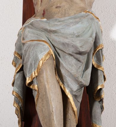Zdjęcie nr 6: Pełnoplastyczna, drążona od tyłu, polichromowana figura Chrystusa przybita do prostego krzyża trzema gwoździami. Sylwetka zmarłego Chrystusa smukła z wyraźnie zaznaczoną muskulaturą i głębokim wcięciem w talii i widocznym układem kostnym klatki piersiowej. Ramiona uniesione wysoko tworzą łuk, dłonie o wyprostowanych palcach. Nogi znacznie ugięte w kolanach, założone prawa na lewą. Głowa pochylona, lekko zwrócona w prawą stronę. Na głowie Chrystus ma założoną pozłacaną koronę cierniową. Twarz podłużna z zapadniętymi policzkami, oczy zamknięte z opadłymi kącikami i ściągniętymi brwiami, nos długi o prostym profilu, usta małe i zamknięte. Włosy długie, opadające na kark, broda krótka i kręcona. Perizonium długie, sięgające połowy łydki, po bokach opadające swobodnie kaskadowymi fałdami. Polichromowane na kolor szary, na brzegu złocone. Nad głową titulus w formie poziomej banderoli z napisem „I.N.R.I.”. W odsłoniętych partiach ciała figura polichromowana naturalistycznie o ciemnej karnacji z zaznaczonymi śladami męki. Krzyż szeroki, prosty, pokryty bejcą. 
