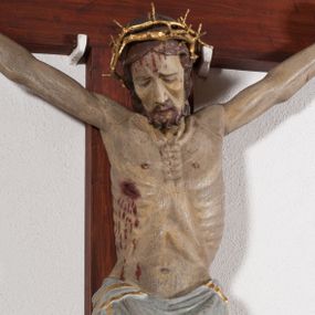 Zdjęcie nr 1: Pełnoplastyczna, drążona od tyłu, polichromowana figura Chrystusa przybita do prostego krzyża trzema gwoździami. Sylwetka zmarłego Chrystusa smukła z wyraźnie zaznaczoną muskulaturą i głębokim wcięciem w talii i widocznym układem kostnym klatki piersiowej. Ramiona uniesione wysoko tworzą łuk, dłonie o wyprostowanych palcach. Nogi znacznie ugięte w kolanach, założone prawa na lewą. Głowa pochylona, lekko zwrócona w prawą stronę. Na głowie Chrystus ma założoną pozłacaną koronę cierniową. Twarz podłużna z zapadniętymi policzkami, oczy zamknięte z opadłymi kącikami i ściągniętymi brwiami, nos długi o prostym profilu, usta małe i zamknięte. Włosy długie, opadające na kark, broda krótka i kręcona. Perizonium długie, sięgające połowy łydki, po bokach opadające swobodnie kaskadowymi fałdami. Polichromowane na kolor szary, na brzegu złocone. Nad głową titulus w formie poziomej banderoli z napisem „I.N.R.I.”. W odsłoniętych partiach ciała figura polichromowana naturalistycznie o ciemnej karnacji z zaznaczonymi śladami męki. Krzyż szeroki, prosty, pokryty bejcą. 
