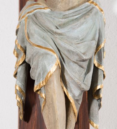 Zdjęcie nr 7: Pełnoplastyczna, drążona od tyłu, polichromowana figura Chrystusa przybita do prostego krzyża trzema gwoździami. Sylwetka zmarłego Chrystusa smukła z wyraźnie zaznaczoną muskulaturą i głębokim wcięciem w talii i widocznym układem kostnym klatki piersiowej. Ramiona uniesione wysoko tworzą łuk, dłonie o wyprostowanych palcach. Nogi znacznie ugięte w kolanach, założone prawa na lewą. Głowa pochylona, lekko zwrócona w prawą stronę. Na głowie Chrystus ma założoną pozłacaną koronę cierniową. Twarz podłużna z zapadniętymi policzkami, oczy zamknięte z opadłymi kącikami i ściągniętymi brwiami, nos długi o prostym profilu, usta małe i zamknięte. Włosy długie, opadające na kark, broda krótka i kręcona. Perizonium długie, sięgające połowy łydki, po bokach opadające swobodnie kaskadowymi fałdami. Polichromowane na kolor szary, na brzegu złocone. Nad głową titulus w formie poziomej banderoli z napisem „I.N.R.I.”. W odsłoniętych partiach ciała figura polichromowana naturalistycznie o ciemnej karnacji z zaznaczonymi śladami męki. Krzyż szeroki, prosty, pokryty bejcą. 
