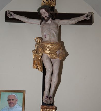 Zdjęcie nr 1: Rzeźba Chrystusa przybita do krzyża czterema gwoździami, ukazana w typie Cristo morte. Ciało o szeroko rozstawionych ramionach, sylwetka szczupła, choć muskularna. Chrystus ma głowę przechyloną na prawe ramię. Twarz szczupła, z wąskim i długim nosem, zamkniętymi oczami, na wpół otwartymi ustami, okolona krótką brodą. Włosy długie, ciemnobrązowe spływające na prawe ramię, na głowie zielona korona cierniowa. Perizonium złocone, zdobione na brzegu koronką, swobodnie oplatające biodra, przewiązane sznurem na prawym boku, z jednym końcem dłuższym, zwisającym wzdłuż prawego uda. Z boku, dłoni, stóp i spod korony cierniowej spływają strużki krwi. Polichromia ciała naturalistyczna. Krzyż gładki, prosty, pomalowany na ciemnobrązowy kolor; nad głową Chrystusa titulus z napisem „INRI” w języku łacińskim, greckim i hebrajskim. U podstawy pionowej belki krzyża złocona i marmoryzowana, wolutowo wygięta konsolka. 