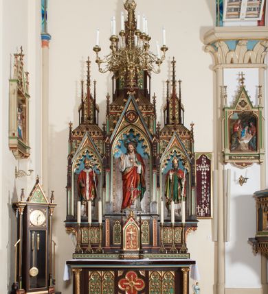 Zdjęcie nr 2: Nastawa ołtarzowa architektoniczna, jednokondygnacyjna, trójosiowa z marmurowym portatylem. Mensa drewniana, prostopadłościenna, na niewielkim cokole. Antepedium płaskorzeźbione, polichromowane, artykułowane dwiema złoconymi kolumienkami. W centrum kwadratowa płycina, w polu której czwórliść ze złoconym krzyżem. Po bokach dwie płaskorzeźbione, kwadratowe płyciny, przedzielone na pół, w każdej maswerk z bogatą dekoracją floralną. Całość zwieńczona wydatnym profilowanym gzymsem. Tabernakulum w formie prostopadłościennej skrzynki, ustawionej na niskim cokole, flankowane dwoma filarami ustawionymi ukośnie i zakończonymi pinaklami. Zwieńczenie tabernakulum w formie prostopadłościennego przyczółka, na którym ustawiony jest krucyfiks. Drzwiczki tabernakulum w kształcie ostrołukowej arkady, w polu której płaskorzeźbiony krucyfiks na tle wici roślinnej utworzonej z kłosów zbóż i winnej latorośli. Retabulum umieszczone na cokole. Predella trójosiowa, zdobiona rzędem pseudomaswerków. Osie kondygnacji flankowane pilastrami z pinaklami zakończonymi kwiatonami. W środkowej osi ostrołukowa nisza zwieńczona wimpergą mieszcząca rzeźbę Najświętszego Serca Pana Jezusa. W osiach bocznych, w analogicznych niszach zwieńczonych wimpergami rzeźby: po lewej św. Wojciecha, po prawej św. Stanisława. Zwieńczenie w formie trzech wieżyczek z pinaklami, kwiatonami i żabkami, część środkowa, najwyższa. Struktura malowana na ciemny brąz, wypełnienia płycin zielone, czerwone i błękitne. Partie ornamentu oraz detale architektoniczne złocone. Ornamentyka neogotycka wypełnia każdą wolną przestrzeń ołtarza: trójliście, maswerki, czołganki etc.

