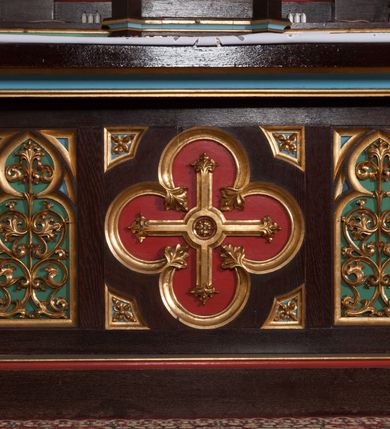 Zdjęcie nr 8: Nastawa ołtarzowa architektoniczna, jednokondygnacyjna, trójosiowa z marmurowym portatylem. Mensa drewniana, prostopadłościenna, na niewielkim cokole. Antepedium płaskorzeźbione, polichromowane, artykułowane dwiema złoconymi kolumienkami. W centrum kwadratowa płycina, w polu której czwórliść ze złoconym krzyżem. Po bokach dwie płaskorzeźbione, kwadratowe płyciny, przedzielone na pół, w każdej maswerk z bogatą dekoracją floralną. Całość zwieńczona wydatnym profilowanym gzymsem. Tabernakulum w formie prostopadłościennej skrzynki, ustawionej na niskim cokole, flankowane dwoma filarami ustawionymi ukośnie i zakończonymi pinaklami. Zwieńczenie tabernakulum w formie prostopadłościennego przyczółka, na którym ustawiony jest krucyfiks. Drzwiczki tabernakulum w kształcie ostrołukowej arkady, w polu której płaskorzeźbiony krucyfiks na tle wici roślinnej utworzonej z kłosów zbóż i winnej latorośli. Retabulum umieszczone na cokole. Predella trójosiowa, zdobiona rzędem pseudomaswerków. Osie kondygnacji flankowane pilastrami z pinaklami zakończonymi kwiatonami. W środkowej osi ostrołukowa nisza zwieńczona wimpergą mieszcząca rzeźbę Najświętszego Serca Pana Jezusa. W osiach bocznych, w analogicznych niszach zwieńczonych wimpergami rzeźby: po lewej św. Wojciecha, po prawej św. Stanisława. Zwieńczenie w formie trzech wieżyczek z pinaklami, kwiatonami i żabkami, część środkowa, najwyższa. Struktura malowana na ciemny brąz, wypełnienia płycin zielone, czerwone i błękitne. Partie ornamentu oraz detale architektoniczne złocone. Ornamentyka neogotycka wypełnia każdą wolną przestrzeń ołtarza: trójliście, maswerki, czołganki etc.

