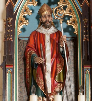 Zdjęcie nr 1: Rzeźba pełnoplastyczna, ustawiona na niskim cokole. Święty ukazany w pozycji stojącej, frontalnie, z wiosłem w prawej dłoni i pastorałem w lewej. Twarz podłużna, z długim i wąskim nosem, wzrokiem skierowanym ku górze, okolona średniej długości brodą. Święty ubrany jest w długą, białą albę, dekorowaną u dołu geometrycznymi wzorami, zieloną rokietę, czerwony ornat z oliwkowo-zieloną podszewką, biały paliusz i złotą infułę na głowie. Wszystkie szaty dekorowane są na brzegach złoconą dekoracją ornamentalną. Polichromia w odsłoniętych partiach ciała naturalistyczna.