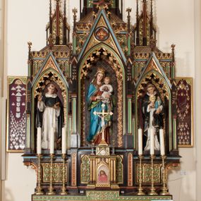 Zdjęcie nr 1: Nastawa ołtarzowa architektoniczna, jednokondygnacyjna, trójosiowa z marmurowym portatylem. Mensa drewniana, prostopadłościenna, na niewielkim cokole. Antepedium płaskorzeźbione, polichromowane, artykułowane dwiema złoconymi kolumienkami. W centrum kwadratowa płycina, w polu której czwórliść ze złoconym krzyżem. Po bokach dwie płaskorzeźbione, kwadratowe płyciny, przedzielone na pół, w każdej maswerk z bogatą dekoracją floralną. Całość zwieńczona wydatnym profilowanym gzymsem. Tabernakulum w formie prostopadłościennej skrzynki, ustawionej na niskim cokole, flankowane dwiema parami kolumn wspierających niepełne belkowanie z prostopadłościennym przyczółkiem, na którym ustawiony jest krucyfiks. Drzwiczki tabernakulum w kształcie ostrołukowej arkady, w polu której płaskorzeźbione przedstawienie Ecce Homo zredukowane do półpostaci Chrystusa w purpurowym płaszczu i koronie cierniowej; w przyłuczach drzwiczek kłosy zbóż i winna latorośl. W zwieńczeniu, na przyczółku monogram IHS, na osi kolumn dwa pinakle. Retabulum umieszczone na cokole. Predella trójosiowa, zdobiona rzędem pseudomaswerków. Osie kondygnacji flankowane pilastrami z pinaklami zwieńczonymi kwiatonami. W środkowej osi ostrołukowa nisza zwieńczona wimpergą mieszcząca rzeźbę Matki Boskiej z Dzieciątkiem. W osiach bocznych, w analogicznych niszach zwieńczonych wimpergami rzeźby: po lewej św. Dominika, po prawej św. Jacka. Zwieńczenie w formie trzech wieżyczek z pinaklami, zdobionymi kwiatonami i żabkami, część środkowa, najwyższa. Struktura malowana na ciemny brąz, wypełnienia płycin zielone, czerwone i błękitne. Partie ornamentu oraz detale architektoniczne złocone. Ornamentyka neogotycka wypełnia każdą wolną przestrzeń ołtarza: trójliście, maswerki, czołganki etc.
