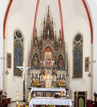 Zdjęcie nr 2: Ołtarz przyścienny, architektoniczny, trójosiowy, jednokondygnacyjny ze zwieńczeniem. Mensa drewniana, prostopadłościenna, na niewielkim cokole. Antepedium płaskorzeźbione, polichromowane, artykułowane złoconymi kolumienkami, zdwojonymi w skrajnych osiach. W centrum prostokątna płycina, w polu której  medalion ze złoconym krzyżem. Po bokach dwie płaskorzeźbione, polichromowane sceny Ofiara Izaaka (z lewej) i Ofiara Melchizedeka (z prawej). Całość zwieńczona wydatnym profilowanym gzymsem. Tabernakulum architektoniczne, trójosiowe z tronem wystawienia. Drzwiczki dekorowane kutą i odlewaną dekoracją w formie ostrołukowych maswerków oraz liter Alfa i Omega. Powyżej głęboka ostrołukowa nisza mieszcząca tron wystawienia. W osiach bocznych pełnoplastyczne, polichromowane figury klęczących aniołów w niszach zwieńczonych ażurowymi baldachimami. Poniżej trójlistne płyciny mieszczące płaskorzeźbione symbole: gołębica Ducha Świętego na tle glorii oraz skrzyżowane klucze i godło zakonu franciszkanów. Retabulum umieszczone na wysokim cokole o licu dekorowanym płaskorzeźbioną dekoracją pseudomaswerkową. Predella na cokole, z dwoma płaskorzeźbionymi, polichromowanymi scenami: Przekazanie kluczy św. Piotrowi (z lewej), Powołanie św. Pawła (z prawej). Sceny flankowane zdwojonymi, złoconymi kolumienkami o roślinnych kapitelach i zwieńczone ażurowym, ostrołukowym baldachimem z motywem trójliścia, żabek i pinakli. W osi środkowej kondygnacji ostrołukowa nisza zwieńczona wimpergą mieszcząca obraz Matki Boskiej Nieustającej Pomocy podtrzymywany przez pełnoplastyczne figury klęczących aniołów. Ponad nim złocony monogram Marii oraz korona. Na zasuwie obraz św. Michała Archanioła. Nisza ujęta dwiema kolumnami ustawionymi na ośmiobocznych cokołach, których trzony zajmują figury: po lewej św. Alfons Maria Liguori (?), po prawej św. Franciszka Ksawerego. Nad rzeźbami wiszą ozdobne baldachimy, nad nimi pełne trzony kolumn z kapitelami, nad którymi ustawiona kolejna para rzeźb. Po lewej rzeźba św. Magdaleny de Pazzi, po prawej figura Matki Boskiej Niepokalanie Poczętej. Obie podpory zwieńczone pinaklami. W osiach bocznych ostrołukowe nisze zamknięte wimpergami mieszczące pełnoplastyczne, polichromowane figury św. Piotra (z lewej) i św. Pawła (z prawej).  Poniżej figur po dwie prostokątne płyciny z płaskorzeźbowymi symbolami i podpisami: gołębicy Ducha Świętego „CONFIRMATIO”, kielicha z krzyżem „BAPTISMUS”, gałązki oliwnej oraz dyscypliny „PENITENTIA” oraz naczynia  i gałązki róż „EXSTREMA UNCTIO”. W zwieńczeniach usytuowane pełnoplastyczne figury aniołów trzymających banderole z napisami: „Adoremus!". Pośrodku grupa rzeźbiarska Ukrzyżowanie z pełnoplastycznymi, polichromowanymi figurami Chrystusa oraz Marii i św. Jana Ewangelisty ustawionymi pod rozbudowanymi, ażurowymi baldachimami. Struktura malowana na ciemny brąz, wypełnienia płycin zielone, czerwone i błękitne. Partie ornamentu oraz detale architektoniczne złocone. Ornamentyka neogotycka wypełnia każdą wolną przestrzeń ołtarza: trójliście, maswerki, czołganki etc.