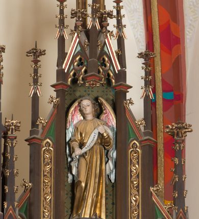 Zdjęcie nr 7: Ołtarz przyścienny, architektoniczny, trójosiowy, jednokondygnacyjny ze zwieńczeniem. Mensa drewniana, prostopadłościenna, na niewielkim cokole. Antepedium płaskorzeźbione, polichromowane, artykułowane złoconymi kolumienkami, zdwojonymi w skrajnych osiach. W centrum prostokątna płycina, w polu której  medalion ze złoconym krzyżem. Po bokach dwie płaskorzeźbione, polichromowane sceny Ofiara Izaaka (z lewej) i Ofiara Melchizedeka (z prawej). Całość zwieńczona wydatnym profilowanym gzymsem. Tabernakulum architektoniczne, trójosiowe z tronem wystawienia. Drzwiczki dekorowane kutą i odlewaną dekoracją w formie ostrołukowych maswerków oraz liter Alfa i Omega. Powyżej głęboka ostrołukowa nisza mieszcząca tron wystawienia. W osiach bocznych pełnoplastyczne, polichromowane figury klęczących aniołów w niszach zwieńczonych ażurowymi baldachimami. Poniżej trójlistne płyciny mieszczące płaskorzeźbione symbole: gołębica Ducha Świętego na tle glorii oraz skrzyżowane klucze i godło zakonu franciszkanów. Retabulum umieszczone na wysokim cokole o licu dekorowanym płaskorzeźbioną dekoracją pseudomaswerkową. Predella na cokole, z dwoma płaskorzeźbionymi, polichromowanymi scenami: Przekazanie kluczy św. Piotrowi (z lewej), Powołanie św. Pawła (z prawej). Sceny flankowane zdwojonymi, złoconymi kolumienkami o roślinnych kapitelach i zwieńczone ażurowym, ostrołukowym baldachimem z motywem trójliścia, żabek i pinakli. W osi środkowej kondygnacji ostrołukowa nisza zwieńczona wimpergą mieszcząca obraz Matki Boskiej Nieustającej Pomocy podtrzymywany przez pełnoplastyczne figury klęczących aniołów. Ponad nim złocony monogram Marii oraz korona. Na zasuwie obraz św. Michała Archanioła. Nisza ujęta dwiema kolumnami ustawionymi na ośmiobocznych cokołach, których trzony zajmują figury: po lewej św. Alfons Maria Liguori (?), po prawej św. Franciszka Ksawerego. Nad rzeźbami wiszą ozdobne baldachimy, nad nimi pełne trzony kolumn z kapitelami, nad którymi ustawiona kolejna para rzeźb. Po lewej rzeźba św. Magdaleny de Pazzi, po prawej figura Matki Boskiej Niepokalanie Poczętej. Obie podpory zwieńczone pinaklami. W osiach bocznych ostrołukowe nisze zamknięte wimpergami mieszczące pełnoplastyczne, polichromowane figury św. Piotra (z lewej) i św. Pawła (z prawej).  Poniżej figur po dwie prostokątne płyciny z płaskorzeźbowymi symbolami i podpisami: gołębicy Ducha Świętego „CONFIRMATIO”, kielicha z krzyżem „BAPTISMUS”, gałązki oliwnej oraz dyscypliny „PENITENTIA” oraz naczynia  i gałązki róż „EXSTREMA UNCTIO”. W zwieńczeniach usytuowane pełnoplastyczne figury aniołów trzymających banderole z napisami: „Adoremus!". Pośrodku grupa rzeźbiarska Ukrzyżowanie z pełnoplastycznymi, polichromowanymi figurami Chrystusa oraz Marii i św. Jana Ewangelisty ustawionymi pod rozbudowanymi, ażurowymi baldachimami. Struktura malowana na ciemny brąz, wypełnienia płycin zielone, czerwone i błękitne. Partie ornamentu oraz detale architektoniczne złocone. Ornamentyka neogotycka wypełnia każdą wolną przestrzeń ołtarza: trójliście, maswerki, czołganki etc.