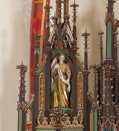 Zdjęcie nr 6: Ołtarz przyścienny, architektoniczny, trójosiowy, jednokondygnacyjny ze zwieńczeniem. Mensa drewniana, prostopadłościenna, na niewielkim cokole. Antepedium płaskorzeźbione, polichromowane, artykułowane złoconymi kolumienkami, zdwojonymi w skrajnych osiach. W centrum prostokątna płycina, w polu której  medalion ze złoconym krzyżem. Po bokach dwie płaskorzeźbione, polichromowane sceny Ofiara Izaaka (z lewej) i Ofiara Melchizedeka (z prawej). Całość zwieńczona wydatnym profilowanym gzymsem. Tabernakulum architektoniczne, trójosiowe z tronem wystawienia. Drzwiczki dekorowane kutą i odlewaną dekoracją w formie ostrołukowych maswerków oraz liter Alfa i Omega. Powyżej głęboka ostrołukowa nisza mieszcząca tron wystawienia. W osiach bocznych pełnoplastyczne, polichromowane figury klęczących aniołów w niszach zwieńczonych ażurowymi baldachimami. Poniżej trójlistne płyciny mieszczące płaskorzeźbione symbole: gołębica Ducha Świętego na tle glorii oraz skrzyżowane klucze i godło zakonu franciszkanów. Retabulum umieszczone na wysokim cokole o licu dekorowanym płaskorzeźbioną dekoracją pseudomaswerkową. Predella na cokole, z dwoma płaskorzeźbionymi, polichromowanymi scenami: Przekazanie kluczy św. Piotrowi (z lewej), Powołanie św. Pawła (z prawej). Sceny flankowane zdwojonymi, złoconymi kolumienkami o roślinnych kapitelach i zwieńczone ażurowym, ostrołukowym baldachimem z motywem trójliścia, żabek i pinakli. W osi środkowej kondygnacji ostrołukowa nisza zwieńczona wimpergą mieszcząca obraz Matki Boskiej Nieustającej Pomocy podtrzymywany przez pełnoplastyczne figury klęczących aniołów. Ponad nim złocony monogram Marii oraz korona. Na zasuwie obraz św. Michała Archanioła. Nisza ujęta dwiema kolumnami ustawionymi na ośmiobocznych cokołach, których trzony zajmują figury: po lewej św. Alfons Maria Liguori (?), po prawej św. Franciszka Ksawerego. Nad rzeźbami wiszą ozdobne baldachimy, nad nimi pełne trzony kolumn z kapitelami, nad którymi ustawiona kolejna para rzeźb. Po lewej rzeźba św. Magdaleny de Pazzi, po prawej figura Matki Boskiej Niepokalanie Poczętej. Obie podpory zwieńczone pinaklami. W osiach bocznych ostrołukowe nisze zamknięte wimpergami mieszczące pełnoplastyczne, polichromowane figury św. Piotra (z lewej) i św. Pawła (z prawej).  Poniżej figur po dwie prostokątne płyciny z płaskorzeźbowymi symbolami i podpisami: gołębicy Ducha Świętego „CONFIRMATIO”, kielicha z krzyżem „BAPTISMUS”, gałązki oliwnej oraz dyscypliny „PENITENTIA” oraz naczynia  i gałązki róż „EXSTREMA UNCTIO”. W zwieńczeniach usytuowane pełnoplastyczne figury aniołów trzymających banderole z napisami: „Adoremus!". Pośrodku grupa rzeźbiarska Ukrzyżowanie z pełnoplastycznymi, polichromowanymi figurami Chrystusa oraz Marii i św. Jana Ewangelisty ustawionymi pod rozbudowanymi, ażurowymi baldachimami. Struktura malowana na ciemny brąz, wypełnienia płycin zielone, czerwone i błękitne. Partie ornamentu oraz detale architektoniczne złocone. Ornamentyka neogotycka wypełnia każdą wolną przestrzeń ołtarza: trójliście, maswerki, czołganki etc.