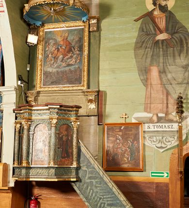 Zdjęcie nr 2: Ambona wisząca, przyścienna. Kosz na planie ośmioboku, na ściankach arkady z malowanymi przedstawieniami św. Walentego, św. Wincentego, św. Jana Nepomucena i bł. Jana Kanonika. Ścianki wydzielone kolumnami kompozytowymi na cokole, dźwigającymi pełne belkowanie wyłamane na ich osi. Parapet w formie silnie wystającego, profilowanego gzymsu. Z prawej strony dostawione jednobiegowe schody z barierką zwieńczoną profilowanym gzymsem. Zaplecek wysoki, ujęty pilastrami dźwiganymi przez konsolki dekorowane liściem; w polu obraz św. Grzegorza Wielkiego. Baldachim na planie trójliścia z lambrekinem z ornamentu roślinnego; utworzony z czterech pałąków dekorowanych akantem, podtrzymujących cokół dla figury św. Michała Archanioła. Figura zwrócona frontalnie, z prawą nogą opartą na fragmencie skały. W lewej ręce trzyma włócznię, w prawej miecz. Ubrany w zbroję, z szeroko rozłożonymi skrzydłami. Na podniebieniu gołębica Ducha Świętego na tle glorii promienistej. Ambona marmoryzowana w tonacji zielono-niebieskiej ze złoconymi detalami i ornamentami.
św. Jana Kantego, św. Jana Nepomucena, św. Walentego i św. Wincentego

św. grzegorz unoszący się nad rzymem