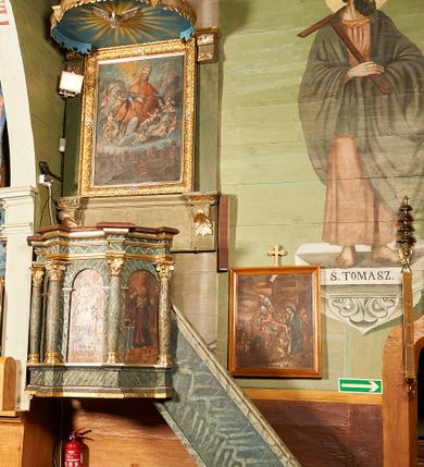 Zdjęcie nr 7: Ambona wisząca, przyścienna. Kosz na planie ośmioboku, na ściankach arkady z malowanymi przedstawieniami św. Walentego, św. Wincentego, św. Jana Nepomucena i bł. Jana Kanonika. Ścianki wydzielone kolumnami kompozytowymi na cokole, dźwigającymi pełne belkowanie wyłamane na ich osi. Parapet w formie silnie wystającego, profilowanego gzymsu. Z prawej strony dostawione jednobiegowe schody z barierką zwieńczoną profilowanym gzymsem. Zaplecek wysoki, ujęty pilastrami dźwiganymi przez konsolki dekorowane liściem; w polu obraz św. Grzegorza Wielkiego. Baldachim na planie trójliścia z lambrekinem z ornamentu roślinnego; utworzony z czterech pałąków dekorowanych akantem, podtrzymujących cokół dla figury św. Michała Archanioła. Figura zwrócona frontalnie, z prawą nogą opartą na fragmencie skały. W lewej ręce trzyma włócznię, w prawej miecz. Ubrany w zbroję, z szeroko rozłożonymi skrzydłami. Na podniebieniu gołębica Ducha Świętego na tle glorii promienistej. Ambona marmoryzowana w tonacji zielono-niebieskiej ze złoconymi detalami i ornamentami.
św. Jana Kantego, św. Jana Nepomucena, św. Walentego i św. Wincentego

św. grzegorz unoszący się nad rzymem