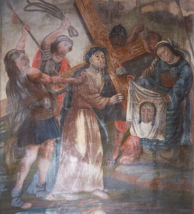 Zdjęcie nr 7: 14 stacji drogi krzyżowej w kształcie stojących prostokątów ujętych w drewniane, profilowane ramy zwieńczone krzyżami. Sceny są narracyjne, wielofiguralne, przedstawiane na tle architektonicznym lub pejzażowym. W centrum wielu z nich znajduje się postać Chrystusa ubranego w różową tunikę i niebieski płaszcz, z nimbem wokół przybranej koroną cierniową głowy. Sceny są tłumne, postacie krępe o zaburzonych proporcjach i uproszczonych rysach twarzy. U dołu kompozycji malowane czarną farbą numery stacji: Stacyja I, Stacyja II etc. Kolorystyka ciemna, ciepła ze zdecydowaną przewagą brązów.