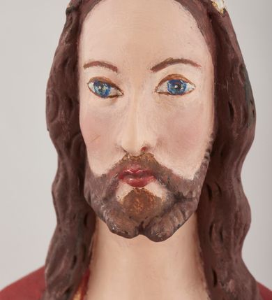 Zdjęcie nr 2: Rzeźba pełnoplastyczna przedstawiająca stojącego Chrystusa Zmartwychwstałego ustawiona na zielonej, owalnej podstawie i profilowanym, sześciobocznym cokoliku. Głowa zwrócona na wprost, twarz wydłużona, wzrok skierowany przed siebie, nos długi prosty, usta pełne. Twarz okala krótki brązowy zarost, włosy brązowe opadające na ramiona. Prawa ręka uniesiona w geście błogosławieństwa, lewa ugięta w łokciu na wysokość pasa, palce złączone. Na rękach, stopach i piersi widoczne ślady męczeństwa. Stopy nagie, biodra otacza złote, płasko sfałdowane perizonium. Płaszcz ciemnoczerwony ze złotą lamówką i białym podbiciem, rzeźbiony w głębokie fałdy. 