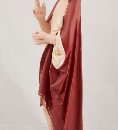 Zdjęcie nr 5: Rzeźba pełnoplastyczna przedstawiająca stojącego Chrystusa Zmartwychwstałego ustawiona na zielonej, owalnej podstawie i profilowanym, sześciobocznym cokoliku. Głowa zwrócona na wprost, twarz wydłużona, wzrok skierowany przed siebie, nos długi prosty, usta pełne. Twarz okala krótki brązowy zarost, włosy brązowe opadające na ramiona. Prawa ręka uniesiona w geście błogosławieństwa, lewa ugięta w łokciu na wysokość pasa, palce złączone. Na rękach, stopach i piersi widoczne ślady męczeństwa. Stopy nagie, biodra otacza złote, płasko sfałdowane perizonium. Płaszcz ciemnoczerwony ze złotą lamówką i białym podbiciem, rzeźbiony w głębokie fałdy. 