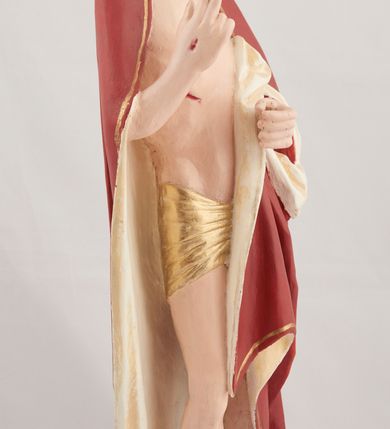 Zdjęcie nr 7: Rzeźba pełnoplastyczna przedstawiająca stojącego Chrystusa Zmartwychwstałego ustawiona na zielonej, owalnej podstawie i profilowanym, sześciobocznym cokoliku. Głowa zwrócona na wprost, twarz wydłużona, wzrok skierowany przed siebie, nos długi prosty, usta pełne. Twarz okala krótki brązowy zarost, włosy brązowe opadające na ramiona. Prawa ręka uniesiona w geście błogosławieństwa, lewa ugięta w łokciu na wysokość pasa, palce złączone. Na rękach, stopach i piersi widoczne ślady męczeństwa. Stopy nagie, biodra otacza złote, płasko sfałdowane perizonium. Płaszcz ciemnoczerwony ze złotą lamówką i białym podbiciem, rzeźbiony w głębokie fałdy. 