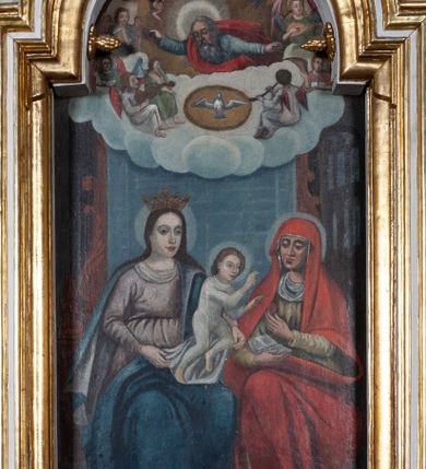 Zdjęcie nr 1: Obraz w kształcie stojącego prostokąta zamkniętego łukiem nadwieszonym, w złoconej i profilowanej ramie. W centrum kompozycji, u dołu przedstawienie św. Anny Samotrzeć. Maria z lewej i św. Anna z prawej siedzą obok siebie, na kolanach Marii stoi mały Jezus, który czyni gest błogosławieństwa w stronę św. Anny. Anna lewą ręką podaje mu owoc, w prawej trzyma otwartą książkę, patrzy na Jezusa. Maria jest ubrana w jasnofioletową suknię przewiązaną w pasie oraz ciemnobłękitny płaszcz z jasnym podbiciem, na głowie ma otwartą koronę. Święta Anna ma na sobie zielonkawą suknię oraz obszerny czerwony płaszcz narzucony na głowę, osłaniający ramiona oraz nogi. Jezus w białej, długiej, przylegającej do ciała tunice. Wszyscy mają nimby wokół głów. Pod ich stopami goła ziemia, na której widać kwitnące kwiaty. W górnej części kompozycji przedstawienie Boga Ojca i gołębicy Ducha Świętego w obłokach. Bóg jest widoczny do połowy ciała, ma rozłożone ręce i spogląda w dół, na siedzącą poniżej grupę. Ma długie siwe włosy oraz brodę, jest ubrany w niebieskawą tunikę i czerwony płaszcz, głowę rozświetla mu szeroki nimb, wokół którego unoszą się cztery uskrzydlone główki anielskie. Poniżej Boga Ojca gołębica z rozpostartymi skrzydłami w świetlistym otoku. Po ich bokach siedzą anioły grające na instrumentach.
 Kolorystyka ciemna, ciepła.