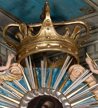 Zdjęcie nr 5: Ołtarz przyścienny, architektoniczny, jednoosiowy, jednokondygnacyjny ze zwieńczeniem i ażurowymi uszakami o falistym brzegu. Mensa prostopadłościenna z portatylem, antepedium ujęte profilowanymi listwami z polem wewnętrznym dekorowanym silnie stylizowanym, malowanym ornamentem o esowatym przebiegu i wolutowych końcach. Na mensie tabernakulum prostopadłościenne, na planie wklęsło-wypukłym, ujęte na narożach taśmami o skręconych końcach, zamknięte falującym gzymsem, pośrodku którego rocaille. Drzwiczki prostokątne, pozłacane z płaskorzeźbionym kielichem z hostią, zamknięte łukiem nadwieszonym. Tabernakulum marmoryzowane na jasnokremowy odcień. Retabulum ujęte parą kolumn kompozytowych ustawionych na niskich cokołach z rozetką, wspierających belkowanie wyłamujące się ponad nimi, z wydatnym, profilowanym gzymsem. Fryz dekorowany girlandami kwiatów w części środkowej, po bokach rozetkami. Nad belkowaniem na osiach kolumn ustawione wazony o żłobionej w dwóch strefach powierzchni. Pole środkowe z niszą ujętą prostokątną, profilowaną ramą, zamkniętą łukiem nadwieszonym. W niszy figura Matki Boskiej z Lourdes. Nad łukiem pozłacana korona otwarta i rozetki. Zwieńczenie półkoliste, ujęte spływami wolutowymi, na których rzeźby uskrzydlonych aniołków. Pośrodku zwieńczenia owalny obraz z przedstawieniem św. Józefa z Dzieciątkiem ujęty ramą uformowaną z obłoków z odchodzącymi promieniami. Nad zwieńczeniem rzeźbiona, złocona korona zamknięta. Całość struktury ołtarza marmoryzowana na kolor niebieski z ciemniejszymi żyłkami; kolumny jasnobrązowe z malowaną z wicią roślinną; ornamenty i profile złocone i srebrzone. 