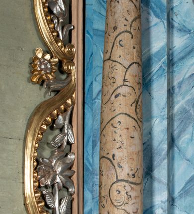 Zdjęcie nr 7: Ołtarz przyścienny, architektoniczny, jednoosiowy, jednokondygnacyjny ze zwieńczeniem i ażurowymi uszakami o falistym brzegu. Mensa prostopadłościenna z portatylem, antepedium ujęte profilowanymi listwami z polem wewnętrznym dekorowanym silnie stylizowanym, malowanym ornamentem o esowatym przebiegu i wolutowych końcach. Na mensie tabernakulum prostopadłościenne, na planie wklęsło-wypukłym, ujęte na narożach taśmami o skręconych końcach, zamknięte falującym gzymsem, pośrodku którego rocaille. Drzwiczki prostokątne, pozłacane z płaskorzeźbionym kielichem z hostią, zamknięte łukiem nadwieszonym. Tabernakulum marmoryzowane na jasnokremowy odcień. Retabulum ujęte parą kolumn kompozytowych ustawionych na niskich cokołach z rozetką, wspierających belkowanie wyłamujące się ponad nimi, z wydatnym, profilowanym gzymsem. Fryz dekorowany girlandami kwiatów w części środkowej, po bokach rozetkami. Nad belkowaniem na osiach kolumn ustawione wazony o żłobionej w dwóch strefach powierzchni. Pole środkowe z niszą ujętą prostokątną, profilowaną ramą, zamkniętą łukiem nadwieszonym. W niszy figura Matki Boskiej z Lourdes. Nad łukiem pozłacana korona otwarta i rozetki. Zwieńczenie półkoliste, ujęte spływami wolutowymi, na których rzeźby uskrzydlonych aniołków. Pośrodku zwieńczenia owalny obraz z przedstawieniem św. Józefa z Dzieciątkiem ujęty ramą uformowaną z obłoków z odchodzącymi promieniami. Nad zwieńczeniem rzeźbiona, złocona korona zamknięta. Całość struktury ołtarza marmoryzowana na kolor niebieski z ciemniejszymi żyłkami; kolumny jasnobrązowe z malowaną z wicią roślinną; ornamenty i profile złocone i srebrzone. 