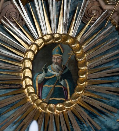 Zdjęcie nr 13: Ołtarz przyścienny, architektoniczny, jednoosiowy, jednokondygnacyjny ze zwieńczeniem i ażurowymi uszakami o falistym brzegu. Mensa w typie sarkofagowym, profilowana, z kamiennym portatylem. Retabulum wklęsłe, ujęte parą kolumn kompozytowych ustawionych na kostkowych cokołach z rozetkami, wspierających belkowanie wyłamujące się ponad nimi, zamknięte wydatnym, profilowanym gzymsem. Fryz dekorowany rozetkami. Nad belkowaniem na osiach kolumn ustawione wazony o marmoryzowanej i żłobionej powierzchni. W polu środkowym głęboka wnęka zamknięta wielobocznie, w której rzeźbiony krucyfiks, po jego bokach malowane postacie Matki Boskiej i Św. Jana na tle pejzażu z architekturą. Zwieńczenie półkoliste ujęte spływami wolutowymi, na których rzeźby aniołków z arma Christi (aniołek po prawej z włócznią, po lewej zaś z gąbką). Pośrodku zwieńczenia owalny obraz z przedstawieniem św. Wojciecha ujęty ramą uformowaną z obłoków z odchodzącymi promieniami. Nad zwieńczeniem rzeźbiona, złocona korona zamknięta. Struktura ołtarza polichromowana, marmoryzowana na odcień niebieski, antepedium z polem marmoryzowanym na kolor beżowy. 