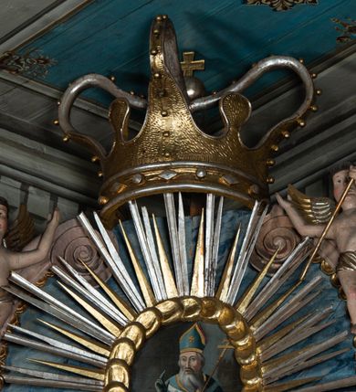 Zdjęcie nr 14: Ołtarz przyścienny, architektoniczny, jednoosiowy, jednokondygnacyjny ze zwieńczeniem i ażurowymi uszakami o falistym brzegu. Mensa w typie sarkofagowym, profilowana, z kamiennym portatylem. Retabulum wklęsłe, ujęte parą kolumn kompozytowych ustawionych na kostkowych cokołach z rozetkami, wspierających belkowanie wyłamujące się ponad nimi, zamknięte wydatnym, profilowanym gzymsem. Fryz dekorowany rozetkami. Nad belkowaniem na osiach kolumn ustawione wazony o marmoryzowanej i żłobionej powierzchni. W polu środkowym głęboka wnęka zamknięta wielobocznie, w której rzeźbiony krucyfiks, po jego bokach malowane postacie Matki Boskiej i Św. Jana na tle pejzażu z architekturą. Zwieńczenie półkoliste ujęte spływami wolutowymi, na których rzeźby aniołków z arma Christi (aniołek po prawej z włócznią, po lewej zaś z gąbką). Pośrodku zwieńczenia owalny obraz z przedstawieniem św. Wojciecha ujęty ramą uformowaną z obłoków z odchodzącymi promieniami. Nad zwieńczeniem rzeźbiona, złocona korona zamknięta. Struktura ołtarza polichromowana, marmoryzowana na odcień niebieski, antepedium z polem marmoryzowanym na kolor beżowy. 