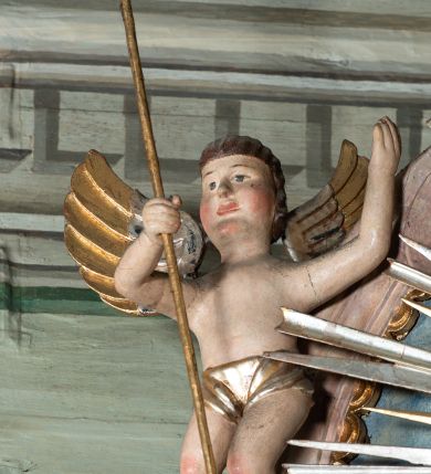 Zdjęcie nr 4: Ołtarz przyścienny, architektoniczny, jednoosiowy, jednokondygnacyjny ze zwieńczeniem i ażurowymi uszakami o falistym brzegu. Mensa w typie sarkofagowym, profilowana, z kamiennym portatylem. Retabulum wklęsłe, ujęte parą kolumn kompozytowych ustawionych na kostkowych cokołach z rozetkami, wspierających belkowanie wyłamujące się ponad nimi, zamknięte wydatnym, profilowanym gzymsem. Fryz dekorowany rozetkami. Nad belkowaniem na osiach kolumn ustawione wazony o marmoryzowanej i żłobionej powierzchni. W polu środkowym głęboka wnęka zamknięta wielobocznie, w której rzeźbiony krucyfiks, po jego bokach malowane postacie Matki Boskiej i Św. Jana na tle pejzażu z architekturą. Zwieńczenie półkoliste ujęte spływami wolutowymi, na których rzeźby aniołków z arma Christi (aniołek po prawej z włócznią, po lewej zaś z gąbką). Pośrodku zwieńczenia owalny obraz z przedstawieniem św. Wojciecha ujęty ramą uformowaną z obłoków z odchodzącymi promieniami. Nad zwieńczeniem rzeźbiona, złocona korona zamknięta. Struktura ołtarza polichromowana, marmoryzowana na odcień niebieski, antepedium z polem marmoryzowanym na kolor beżowy. 