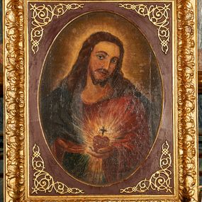 Zdjęcie nr 1: Obraz z przedstawieniem Najświętszego Serca Jezusa ukazanego w półpostaci, frontalnie z głową przechyloną w stronę lewego barku, sercem w lewej dłoni i wskazujący na nie prawą dłonią. Głowa zwrócona delikatnie w lewo, wzrok skierowany na widza, nos prosty, usta wąskie. Twarz okala bujny, ciemnobrązowy zarost, falowane włosy opadają na ramiona i plecy. Wokół głowy znajduje się świetlisty nimb. Chrystus ubrany jest w czerwoną suknię z długimi rękawami i granatowy płaszcz, który przerzucony ma przez prawy bark. Trzymane w dłoni serce jest otoczone koroną cierniową i zwieńczone krzyżem łacińskim, otacza je jasna, promienista gloria. Tło ciemnobrązowe, jaśniejące wokół głowy Chrystusa. Obraz ujęty jest w bogato zdobione prostokątne i profilowane ramy o owalnym świetle, dekorowane w narożach stylizowanym ornamentem cęgowym.