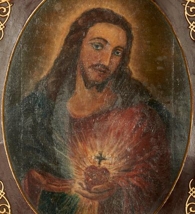 Zdjęcie nr 3: Obraz z przedstawieniem Najświętszego Serca Jezusa ukazanego w półpostaci, frontalnie z głową przechyloną w stronę lewego barku, sercem w lewej dłoni i wskazujący na nie prawą dłonią. Głowa zwrócona delikatnie w lewo, wzrok skierowany na widza, nos prosty, usta wąskie. Twarz okala bujny, ciemnobrązowy zarost, falowane włosy opadają na ramiona i plecy. Wokół głowy znajduje się świetlisty nimb. Chrystus ubrany jest w czerwoną suknię z długimi rękawami i granatowy płaszcz, który przerzucony ma przez prawy bark. Trzymane w dłoni serce jest otoczone koroną cierniową i zwieńczone krzyżem łacińskim, otacza je jasna, promienista gloria. Tło ciemnobrązowe, jaśniejące wokół głowy Chrystusa. Obraz ujęty jest w bogato zdobione prostokątne i profilowane ramy o owalnym świetle, dekorowane w narożach stylizowanym ornamentem cęgowym.