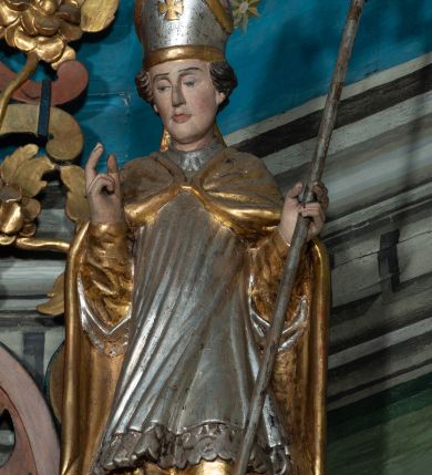 Zdjęcie nr 5: Nastawa ołtarzowa architektoniczna, dwukondygnacyjna, z bramkami, na podwójnym cokole. Pierwsza kondygnacja trójosiowa, ujęta dwiema parami kolumn o kapitelach korynckich, dźwigających pełne belkowanie wyłamane na ich osi i przerwane w partii pola środkowego, nad którym gzyms przyjmuje formę łuku odcinkowego. Na osi środkowych kolumn przerwany, falisty przyczółek. Pole obrazowe w formie stojącego prostokąta zamkniętego łukiem nadwieszonym, w nim obraz Matki Boskiej z Dzieciątkiem (na zasuwie Matki Boskiej Niepokalanie Poczętej) w profilowanej ramie; w podłuczu stylizowany, dekorowany kwiatami monogram Maryjny; u spodu lambrekin. Druga kondygnacja jednoosiowa, ujęta parą kolumn o kapitelach korynckich, dźwigających pełne belkowanie wyłamane wielokrotnie na ich osi oraz przerwany, falisty przyczółek. W drugiej kondygnacji obraz św. Piotra i św. Pawła w ramie dekorowanej stylizowanym akantem z elementami małżowiny oraz wieńcem; zwieńczonej rozetą z liśćmi akantu. Pole obrazowe ujęte suchym akantem oraz parą festonów z owocami.  Zwieńczenie w kształcie glorii promienistej z gołębicą Ducha Świętego na tle obłoków. Cokół dekorowany uskrzydlonymi główkami anielskimi i akantem. Fryz zdobiony rozetami i suchym akantem oraz pasem akantu z elementami małżowiny. Pierwsza kondygnacja ujęta uszami w formie wolut z elementami roślinnymi i kwiatami. Na przerwanym przyczółku siedząca para puttów; na gzymsie figury św. Wojciecha i św. Stanisława biskupa. Fryz dekorowany ornamentem roślinnym oraz pasem akantu z elementami małżowiny na osi kolumn oraz rozetami w centrum. Druga kondygnacja ujęta uszami w formie cęgów przeplatanych gałązką różaną. Na gzymsie w centrum postument zdobiony winną latoroślą, na nim wazon z elementami roślinnymi. Na przerwanym przyczółku para puttów. Podstawę dla glorii tworzy suchy akant.  Ołtarz z kamienną mensą. Antepedium w formie ramy z płaskorzeźbionym przedstawieniem Ostatniej Wieczerzy. Ołtarz w drewnianej obudowie, ujęty spływami wolutowymi dekorowanymi kogucim grzebieniem, zakończony podwójnym parapetem. Tabernakulum o falistej, wypukłej ścianie frontowej; ujęte pilastrami w formie spływów wolutowych dekorowanych kogucim grzebieniem, dźwigającymi profilowany gzyms, wyłamany na ich osi z palmetą w centrum. Drzwiczki w formie stojącego prostokąta zamkniętego łukiem nadwieszonym z apliką w postaci kielicha z hostią w glorii; ujęte rocaille&#039;m. Tron wystawienia w formie niszy flankowanej kolumnami na cokołach o żłobkowanych trzonach, dźwigających imposty. Całość zamknięta wybrzuszonym gzymsem. W konsze rozeta w otoczeniu liści. Tron ujęty uszami w postaci cęgów przeplatanych gałązkami różanymi. Po bokach ołtarza bramki zamknięte przeciwstawnie zwróconymi wolutami dekorowanymi uskrzydlonymi główkami anielskimi. Przejścia w formie prostokąta zamkniętego trójbocznie, dekorowanego podwójną listewką; na końcach bramek dwie figury św. Wawrzyńca i św. Szczepana.
 Nastawa marmoryzowana na kolor niebieski, z czerwonymi elementami oraz złoconymi i srebrzonymi detalami architektonicznymi i ornamentyką; tabernakulum złocone i srebrzone, miejscami marmoryzowane na kolor niebieski; kolumienki szare. 