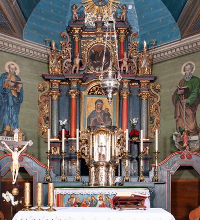 Zdjęcie nr 1: Nastawa ołtarzowa architektoniczna, dwukondygnacyjna, z bramkami, na podwójnym cokole. Pierwsza kondygnacja trójosiowa, ujęta dwiema parami kolumn o kapitelach korynckich, dźwigających pełne belkowanie wyłamane na ich osi i przerwane w partii pola środkowego, nad którym gzyms przyjmuje formę łuku odcinkowego. Na osi środkowych kolumn przerwany, falisty przyczółek. Pole obrazowe w formie stojącego prostokąta zamkniętego łukiem nadwieszonym, w nim obraz Matki Boskiej z Dzieciątkiem (na zasuwie Matki Boskiej Niepokalanie Poczętej) w profilowanej ramie; w podłuczu stylizowany, dekorowany kwiatami monogram Maryjny; u spodu lambrekin. Druga kondygnacja jednoosiowa, ujęta parą kolumn o kapitelach korynckich, dźwigających pełne belkowanie wyłamane wielokrotnie na ich osi oraz przerwany, falisty przyczółek. W drugiej kondygnacji obraz św. Piotra i św. Pawła w ramie dekorowanej stylizowanym akantem z elementami małżowiny oraz wieńcem; zwieńczonej rozetą z liśćmi akantu. Pole obrazowe ujęte suchym akantem oraz parą festonów z owocami.  Zwieńczenie w kształcie glorii promienistej z gołębicą Ducha Świętego na tle obłoków. Cokół dekorowany uskrzydlonymi główkami anielskimi i akantem. Fryz zdobiony rozetami i suchym akantem oraz pasem akantu z elementami małżowiny. Pierwsza kondygnacja ujęta uszami w formie wolut z elementami roślinnymi i kwiatami. Na przerwanym przyczółku siedząca para puttów; na gzymsie figury św. Wojciecha i św. Stanisława biskupa. Fryz dekorowany ornamentem roślinnym oraz pasem akantu z elementami małżowiny na osi kolumn oraz rozetami w centrum. Druga kondygnacja ujęta uszami w formie cęgów przeplatanych gałązką różaną. Na gzymsie w centrum postument zdobiony winną latoroślą, na nim wazon z elementami roślinnymi. Na przerwanym przyczółku para puttów. Podstawę dla glorii tworzy suchy akant.  Ołtarz z kamienną mensą. Antepedium w formie ramy z płaskorzeźbionym przedstawieniem Ostatniej Wieczerzy. Ołtarz w drewnianej obudowie, ujęty spływami wolutowymi dekorowanymi kogucim grzebieniem, zakończony podwójnym parapetem. Tabernakulum o falistej, wypukłej ścianie frontowej; ujęte pilastrami w formie spływów wolutowych dekorowanych kogucim grzebieniem, dźwigającymi profilowany gzyms, wyłamany na ich osi z palmetą w centrum. Drzwiczki w formie stojącego prostokąta zamkniętego łukiem nadwieszonym z apliką w postaci kielicha z hostią w glorii; ujęte rocaille'm. Tron wystawienia w formie niszy flankowanej kolumnami na cokołach o żłobkowanych trzonach, dźwigających imposty. Całość zamknięta wybrzuszonym gzymsem. W konsze rozeta w otoczeniu liści. Tron ujęty uszami w postaci cęgów przeplatanych gałązkami różanymi. Po bokach ołtarza bramki zamknięte przeciwstawnie zwróconymi wolutami dekorowanymi uskrzydlonymi główkami anielskimi. Przejścia w formie prostokąta zamkniętego trójbocznie, dekorowanego podwójną listewką; na końcach bramek dwie figury św. Wawrzyńca i św. Szczepana.
 Nastawa marmoryzowana na kolor niebieski, z czerwonymi elementami oraz złoconymi i srebrzonymi detalami architektonicznymi i ornamentyką; tabernakulum złocone i srebrzone, miejscami marmoryzowane na kolor niebieski; kolumienki szare. 