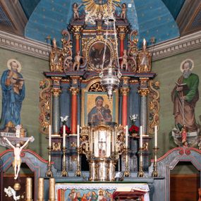 Zdjęcie nr 1: Nastawa ołtarzowa architektoniczna, dwukondygnacyjna, z bramkami, na podwójnym cokole. Pierwsza kondygnacja trójosiowa, ujęta dwiema parami kolumn o kapitelach korynckich, dźwigających pełne belkowanie wyłamane na ich osi i przerwane w partii pola środkowego, nad którym gzyms przyjmuje formę łuku odcinkowego. Na osi środkowych kolumn przerwany, falisty przyczółek. Pole obrazowe w formie stojącego prostokąta zamkniętego łukiem nadwieszonym, w nim obraz Matki Boskiej z Dzieciątkiem (na zasuwie Matki Boskiej Niepokalanie Poczętej) w profilowanej ramie; w podłuczu stylizowany, dekorowany kwiatami monogram Maryjny; u spodu lambrekin. Druga kondygnacja jednoosiowa, ujęta parą kolumn o kapitelach korynckich, dźwigających pełne belkowanie wyłamane wielokrotnie na ich osi oraz przerwany, falisty przyczółek. W drugiej kondygnacji obraz św. Piotra i św. Pawła w ramie dekorowanej stylizowanym akantem z elementami małżowiny oraz wieńcem; zwieńczonej rozetą z liśćmi akantu. Pole obrazowe ujęte suchym akantem oraz parą festonów z owocami.  Zwieńczenie w kształcie glorii promienistej z gołębicą Ducha Świętego na tle obłoków. Cokół dekorowany uskrzydlonymi główkami anielskimi i akantem. Fryz zdobiony rozetami i suchym akantem oraz pasem akantu z elementami małżowiny. Pierwsza kondygnacja ujęta uszami w formie wolut z elementami roślinnymi i kwiatami. Na przerwanym przyczółku siedząca para puttów; na gzymsie figury św. Wojciecha i św. Stanisława biskupa. Fryz dekorowany ornamentem roślinnym oraz pasem akantu z elementami małżowiny na osi kolumn oraz rozetami w centrum. Druga kondygnacja ujęta uszami w formie cęgów przeplatanych gałązką różaną. Na gzymsie w centrum postument zdobiony winną latoroślą, na nim wazon z elementami roślinnymi. Na przerwanym przyczółku para puttów. Podstawę dla glorii tworzy suchy akant.  Ołtarz z kamienną mensą. Antepedium w formie ramy z płaskorzeźbionym przedstawieniem Ostatniej Wieczerzy. Ołtarz w drewnianej obudowie, ujęty spływami wolutowymi dekorowanymi kogucim grzebieniem, zakończony podwójnym parapetem. Tabernakulum o falistej, wypukłej ścianie frontowej; ujęte pilastrami w formie spływów wolutowych dekorowanych kogucim grzebieniem, dźwigającymi profilowany gzyms, wyłamany na ich osi z palmetą w centrum. Drzwiczki w formie stojącego prostokąta zamkniętego łukiem nadwieszonym z apliką w postaci kielicha z hostią w glorii; ujęte rocaille&#039;m. Tron wystawienia w formie niszy flankowanej kolumnami na cokołach o żłobkowanych trzonach, dźwigających imposty. Całość zamknięta wybrzuszonym gzymsem. W konsze rozeta w otoczeniu liści. Tron ujęty uszami w postaci cęgów przeplatanych gałązkami różanymi. Po bokach ołtarza bramki zamknięte przeciwstawnie zwróconymi wolutami dekorowanymi uskrzydlonymi główkami anielskimi. Przejścia w formie prostokąta zamkniętego trójbocznie, dekorowanego podwójną listewką; na końcach bramek dwie figury św. Wawrzyńca i św. Szczepana.
 Nastawa marmoryzowana na kolor niebieski, z czerwonymi elementami oraz złoconymi i srebrzonymi detalami architektonicznymi i ornamentyką; tabernakulum złocone i srebrzone, miejscami marmoryzowane na kolor niebieski; kolumienki szare. 