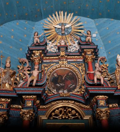 Zdjęcie nr 11: Nastawa ołtarzowa architektoniczna, dwukondygnacyjna, z bramkami, na podwójnym cokole. Pierwsza kondygnacja trójosiowa, ujęta dwiema parami kolumn o kapitelach korynckich, dźwigających pełne belkowanie wyłamane na ich osi i przerwane w partii pola środkowego, nad którym gzyms przyjmuje formę łuku odcinkowego. Na osi środkowych kolumn przerwany, falisty przyczółek. Pole obrazowe w formie stojącego prostokąta zamkniętego łukiem nadwieszonym, w nim obraz Matki Boskiej z Dzieciątkiem (na zasuwie Matki Boskiej Niepokalanie Poczętej) w profilowanej ramie; w podłuczu stylizowany, dekorowany kwiatami monogram Maryjny; u spodu lambrekin. Druga kondygnacja jednoosiowa, ujęta parą kolumn o kapitelach korynckich, dźwigających pełne belkowanie wyłamane wielokrotnie na ich osi oraz przerwany, falisty przyczółek. W drugiej kondygnacji obraz św. Piotra i św. Pawła w ramie dekorowanej stylizowanym akantem z elementami małżowiny oraz wieńcem; zwieńczonej rozetą z liśćmi akantu. Pole obrazowe ujęte suchym akantem oraz parą festonów z owocami.  Zwieńczenie w kształcie glorii promienistej z gołębicą Ducha Świętego na tle obłoków. Cokół dekorowany uskrzydlonymi główkami anielskimi i akantem. Fryz zdobiony rozetami i suchym akantem oraz pasem akantu z elementami małżowiny. Pierwsza kondygnacja ujęta uszami w formie wolut z elementami roślinnymi i kwiatami. Na przerwanym przyczółku siedząca para puttów; na gzymsie figury św. Wojciecha i św. Stanisława biskupa. Fryz dekorowany ornamentem roślinnym oraz pasem akantu z elementami małżowiny na osi kolumn oraz rozetami w centrum. Druga kondygnacja ujęta uszami w formie cęgów przeplatanych gałązką różaną. Na gzymsie w centrum postument zdobiony winną latoroślą, na nim wazon z elementami roślinnymi. Na przerwanym przyczółku para puttów. Podstawę dla glorii tworzy suchy akant.  Ołtarz z kamienną mensą. Antepedium w formie ramy z płaskorzeźbionym przedstawieniem Ostatniej Wieczerzy. Ołtarz w drewnianej obudowie, ujęty spływami wolutowymi dekorowanymi kogucim grzebieniem, zakończony podwójnym parapetem. Tabernakulum o falistej, wypukłej ścianie frontowej; ujęte pilastrami w formie spływów wolutowych dekorowanych kogucim grzebieniem, dźwigającymi profilowany gzyms, wyłamany na ich osi z palmetą w centrum. Drzwiczki w formie stojącego prostokąta zamkniętego łukiem nadwieszonym z apliką w postaci kielicha z hostią w glorii; ujęte rocaille'm. Tron wystawienia w formie niszy flankowanej kolumnami na cokołach o żłobkowanych trzonach, dźwigających imposty. Całość zamknięta wybrzuszonym gzymsem. W konsze rozeta w otoczeniu liści. Tron ujęty uszami w postaci cęgów przeplatanych gałązkami różanymi. Po bokach ołtarza bramki zamknięte przeciwstawnie zwróconymi wolutami dekorowanymi uskrzydlonymi główkami anielskimi. Przejścia w formie prostokąta zamkniętego trójbocznie, dekorowanego podwójną listewką; na końcach bramek dwie figury św. Wawrzyńca i św. Szczepana.
 Nastawa marmoryzowana na kolor niebieski, z czerwonymi elementami oraz złoconymi i srebrzonymi detalami architektonicznymi i ornamentyką; tabernakulum złocone i srebrzone, miejscami marmoryzowane na kolor niebieski; kolumienki szare. 