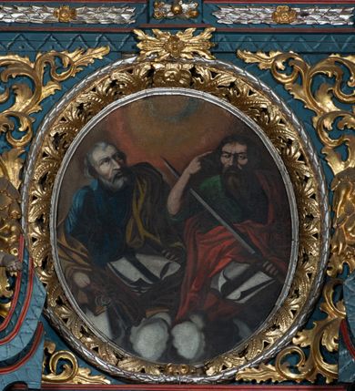 Zdjęcie nr 2: Obraz w formie owalu, w centrum dwie półpostacie świętych na obłokach. Po prawej św. Paweł, zwrócony w trzech czwartych w prawo. W lewej ręce trzyma miecz zwrócony ku górze, prawą unosi, wskazując głowę. Twarz ascetyczna, o ściągniętych brwiach, okolona długą brodą opadającą na pierś. Włosy krótkie, ciemne. Święty jest ubrany w zieloną tunikę oraz przerzucony diagonalnie czerwony płaszcz. Na jego kolanach księga. Po lewej stronie św. Piotr zwrócony w trzech czwartych w lewą stronę,  z głową uniesioną ku górze. W prawej ręce trzyma klucze, lewą przytrzymuje leżącą przed nim księgę. Twarz podłużna o starczych rysach, okolona siwą brodą; włosy krótkie, siwe. Ubrany jest w granatową tunikę oraz żółty płaszcz przerzucony przez lewe ramię. Tło w formie poświaty w układzie koncentrycznych kręgów. Kolorystyka kontrastowa, intensywna, o silnym światłocieniu.