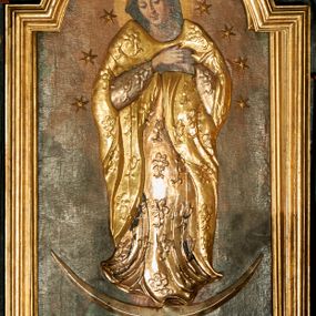Zdjęcie nr 1: Obraz w kształcie stojącego prostokąta zamkniętego łukiem nadwieszonym w profilowanej, złoconej ramie. W centrum kompozycji ukazana Matka Boska w całej postaci, stojąca na półksiężycu z zaznaczonymi rysami twarzy oraz globie, depcząca węża trzymającego w paszczy jabłko. Obie ręce ma złożone na piersi, głowę skłania. Ma owalną, delikatną twarz, spogląda w dół, ma ciemne oczy przesłonięte dużymi powiekami, wąski nos i niewielkie usta oraz długie, ciemne włosy opadające na plecy. Jej głowę otacza świetlisty nimb, ramiona i głowę wieniec z 10 gwiazd. Ubranie jest przysłonięte płaskorzeźbioną, drewnianą sukienkę w postaci tuniki i płaszcza dekorowanych kwiatami, stopy bose. Tło ciemnobrązowe, niejednolite, kolorystyka ciepła, brunatna.
