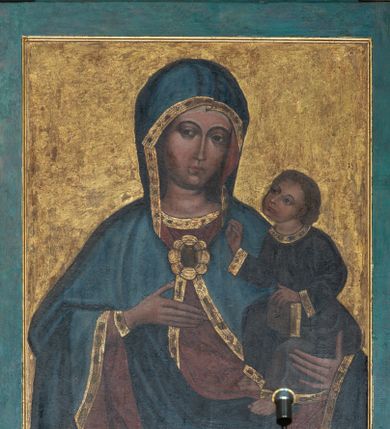 Zdjęcie nr 1: Obraz w formie stojącego prostokąta, w błękitnej ramie. W centrum półpostać Matki Boskiej zwróconej na wprost. Maria lewą ręką podtrzymuje Dzieciątko, prawą uniesioną na wysokość piersi wskazuje na nie. Twarz ma owalną, o wyraźnych rysach oczu i brwi, długim, wąskim nosie i małych ustach. Matka Boska jest ubrana w czerwoną suknię spodnią ze złoconą lamówką oraz granatowy płaszcz, podbity czerwienią, zdobiony złoconą lamówką, okrywający ramiona i głowę oraz spięty na piersi fibulą w formie rozety. Dzieciątko zwrócone w trzech czwartych w prawo, z głową uniesioną do góry. Lewą ręką podtrzymuje na kolanach księgę, prawą unosi w geście błogosławieństwa. Twarz ma okrągłą, o wyraźnych rysach, dużych oczach, wąskim nosie i małych ustach. Włosy jasne, krótkie, kręcone. Jezus jest ubrany w szarą tunikę przepasaną w talii ze złoconymi lamówkami. Tło jednolite złocone. Kolorystyka kontrastowa, wyrazista; silny światłocień.