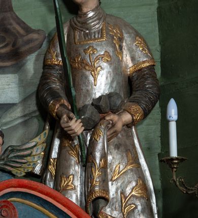 Zdjęcie nr 1: Rzeźba drążona, ścięta z tyłu. Figura zwrócona na wprost, z głową skręconą lekko w prawo. Ręce opuszczone na dół, w prawej zielona palma męczeństwa, w lewej szare kamienie. Twarz pełna, o małych oczach, długim nosie i wąskich ustach. Włosy krótkie, kręcone. Święty jest ubrany w szarą albę, srebrzoną u dołu z rękawami zakończonymi złotą lamówką, srebrny humerał oraz dalmatykę dekorowaną ukwieconymi gałązkami. Polichromia naturalistyczna w partiach ciała.