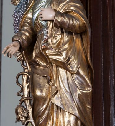 Zdjęcie nr 3: Ołtarz architektoniczny, jednoosiowy, z wydzieloną predellą, jednokondygnacyjny, ze zwieńczeniem. Mensa drewniana na skrzyniowej prostopadłościennej tumbie. Antependium w prostokątnej profilowanej ramie zdobione trzema płycinami, w których pośrodku płaskorzeźbione przedstawienie Chrystusa upadającego pod krzyżem, po bokach motywy serca. Nastawa ujęta kwadratowymi w rzucie filarami przyściennymi o kanelowanych trzonach, z kompozytowymi kapitelami, dźwigającymi występującymi nad nimi uproszczone belkowanie i profilowany gzyms, przerwany nad polem środkowym. Na tle filarów ustawione na konsolach rzeźby: Matka Boska Bolesna po lewej i św. Jan Ewangelista po prawej stronie. W polu środkowym barokowy obraz z przedstawieniem Ukrzyżowania w ozdobnej ramie. W przyłuczach ramy uskrzydlone główki aniołków. Poniżej obrazu nałożony motyw kielicha, po bokach dwie banderole z inskrypcją: BŁOGOSŁAWIONY KTÓRY / IDZIE W IMIĘ PAŃSKIE. Zwieńczenie w kształcie aedikuli o wklęsłych bokach, zamkniętej łukiem półkolistym nadwieszonym. W polu zwieńczenia obraz ukazujący św. Rozalię. Na gzymsie koronującym rzeźbione przedstawienie Boga Ojca oraz Gołębica Ducha Świętego. Poniżej obrazu medalion ze złoconymi literami: IHS. W osiach podpór dwa uskrzydlone anioły trzymające Arma Christi (trzcinę z gąbką i włócznię). Nastawa flankowana ażurowymi, płasko rzeźbionymi uszami w formie wici winnej latorośli z kiściami gron i liśćmi.  Struktura malowana na kolor brązowy, rzeźby, detale architektoniczne i ornamenty złocone lub srebrzone, część laserowana.