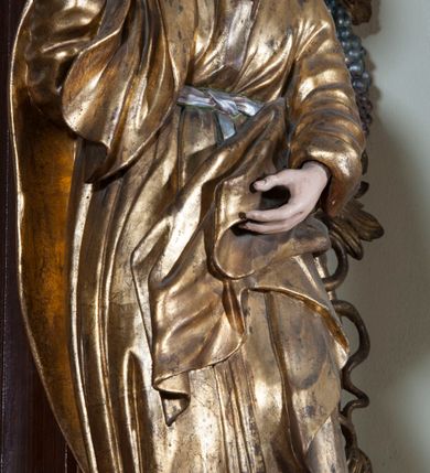 Zdjęcie nr 5: Ołtarz architektoniczny, jednoosiowy, z wydzieloną predellą, jednokondygnacyjny, ze zwieńczeniem. Mensa drewniana na skrzyniowej prostopadłościennej tumbie. Antependium w prostokątnej profilowanej ramie zdobione trzema płycinami, w których pośrodku płaskorzeźbione przedstawienie Chrystusa upadającego pod krzyżem, po bokach motywy serca. Nastawa ujęta kwadratowymi w rzucie filarami przyściennymi o kanelowanych trzonach, z kompozytowymi kapitelami, dźwigającymi występującymi nad nimi uproszczone belkowanie i profilowany gzyms, przerwany nad polem środkowym. Na tle filarów ustawione na konsolach rzeźby: Matka Boska Bolesna po lewej i św. Jan Ewangelista po prawej stronie. W polu środkowym barokowy obraz z przedstawieniem Ukrzyżowania w ozdobnej ramie. W przyłuczach ramy uskrzydlone główki aniołków. Poniżej obrazu nałożony motyw kielicha, po bokach dwie banderole z inskrypcją: BŁOGOSŁAWIONY KTÓRY / IDZIE W IMIĘ PAŃSKIE. Zwieńczenie w kształcie aedikuli o wklęsłych bokach, zamkniętej łukiem półkolistym nadwieszonym. W polu zwieńczenia obraz ukazujący św. Rozalię. Na gzymsie koronującym rzeźbione przedstawienie Boga Ojca oraz Gołębica Ducha Świętego. Poniżej obrazu medalion ze złoconymi literami: IHS. W osiach podpór dwa uskrzydlone anioły trzymające Arma Christi (trzcinę z gąbką i włócznię). Nastawa flankowana ażurowymi, płasko rzeźbionymi uszami w formie wici winnej latorośli z kiściami gron i liśćmi.  Struktura malowana na kolor brązowy, rzeźby, detale architektoniczne i ornamenty złocone lub srebrzone, część laserowana.