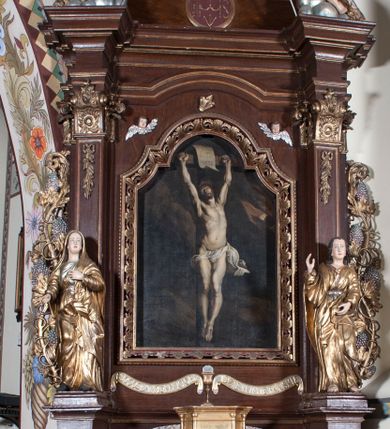 Zdjęcie nr 1: Ołtarz architektoniczny, jednoosiowy, z wydzieloną predellą, jednokondygnacyjny, ze zwieńczeniem. Mensa drewniana na skrzyniowej prostopadłościennej tumbie. Antependium w prostokątnej profilowanej ramie zdobione trzema płycinami, w których pośrodku płaskorzeźbione przedstawienie Chrystusa upadającego pod krzyżem, po bokach motywy serca. Nastawa ujęta kwadratowymi w rzucie filarami przyściennymi o kanelowanych trzonach, z kompozytowymi kapitelami, dźwigającymi występującymi nad nimi uproszczone belkowanie i profilowany gzyms, przerwany nad polem środkowym. Na tle filarów ustawione na konsolach rzeźby: Matka Boska Bolesna po lewej i św. Jan Ewangelista po prawej stronie. W polu środkowym barokowy obraz z przedstawieniem Ukrzyżowania w ozdobnej ramie. W przyłuczach ramy uskrzydlone główki aniołków. Poniżej obrazu nałożony motyw kielicha, po bokach dwie banderole z inskrypcją: BŁOGOSŁAWIONY KTÓRY / IDZIE W IMIĘ PAŃSKIE. Zwieńczenie w kształcie aedikuli o wklęsłych bokach, zamkniętej łukiem półkolistym nadwieszonym. W polu zwieńczenia obraz ukazujący św. Rozalię. Na gzymsie koronującym rzeźbione przedstawienie Boga Ojca oraz Gołębica Ducha Świętego. Poniżej obrazu medalion ze złoconymi literami: IHS. W osiach podpór dwa uskrzydlone anioły trzymające Arma Christi (trzcinę z gąbką i włócznię). Nastawa flankowana ażurowymi, płasko rzeźbionymi uszami w formie wici winnej latorośli z kiściami gron i liśćmi.  Struktura malowana na kolor brązowy, rzeźby, detale architektoniczne i ornamenty złocone lub srebrzone, część laserowana.