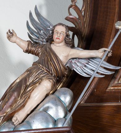 Zdjęcie nr 11: Ołtarz architektoniczny, jednoosiowy, z wydzieloną predellą, jednokondygnacyjny, ze zwieńczeniem. Mensa drewniana na skrzyniowej prostopadłościennej tumbie. Antependium w prostokątnej profilowanej ramie zdobione trzema płycinami, w których pośrodku płaskorzeźbione przedstawienie Chrystusa upadającego pod krzyżem, po bokach motywy serca. Nastawa ujęta kwadratowymi w rzucie filarami przyściennymi o kanelowanych trzonach, z kompozytowymi kapitelami, dźwigającymi występującymi nad nimi uproszczone belkowanie i profilowany gzyms, przerwany nad polem środkowym. Na tle filarów ustawione na konsolach rzeźby: Matka Boska Bolesna po lewej i św. Jan Ewangelista po prawej stronie. W polu środkowym barokowy obraz z przedstawieniem Ukrzyżowania w ozdobnej ramie. W przyłuczach ramy uskrzydlone główki aniołków. Poniżej obrazu nałożony motyw kielicha, po bokach dwie banderole z inskrypcją: BŁOGOSŁAWIONY KTÓRY / IDZIE W IMIĘ PAŃSKIE. Zwieńczenie w kształcie aedikuli o wklęsłych bokach, zamkniętej łukiem półkolistym nadwieszonym. W polu zwieńczenia obraz ukazujący św. Rozalię. Na gzymsie koronującym rzeźbione przedstawienie Boga Ojca oraz Gołębica Ducha Świętego. Poniżej obrazu medalion ze złoconymi literami: IHS. W osiach podpór dwa uskrzydlone anioły trzymające Arma Christi (trzcinę z gąbką i włócznię). Nastawa flankowana ażurowymi, płasko rzeźbionymi uszami w formie wici winnej latorośli z kiściami gron i liśćmi.  Struktura malowana na kolor brązowy, rzeźby, detale architektoniczne i ornamenty złocone lub srebrzone, część laserowana.