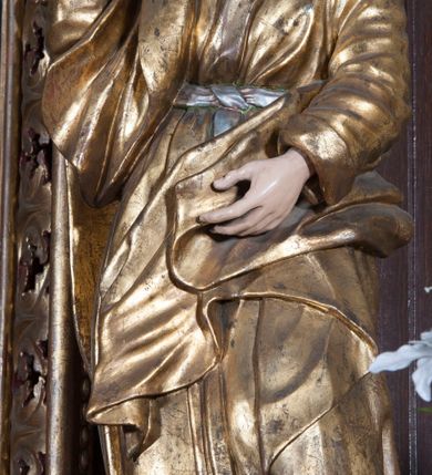 Zdjęcie nr 3: Rzeźba pełnoplastyczna, przyścienna; przedstawienie św. Jana Ewangelisty ukazanego w całej postaci, stojącego w lekkim kontrapoście, z prawą nogą ugiętą w kolanie, zwróconego lekko w prawo i zapatrzonego przed siebie. Ręce ugięte w łokciach, prawa z dłonią wzniesioną ku górze, lewa z dłonią na wysokości brzucha. Twarz młodzieńcza, o jasnej karnacji i delikatnych rysach, z wysokim czołem, bez zarostu, okolona włosami sięgającymi po bokach do uszu, a z tyłu spływającymi na plecy. Ubrana w długą luźną, przepasaną w talii suknię z długimi szerokimi rękawami, osłania przód postaci.